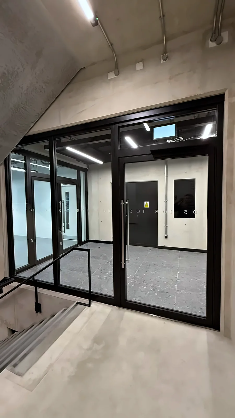 A glazed fire screen and door at a stair landing.