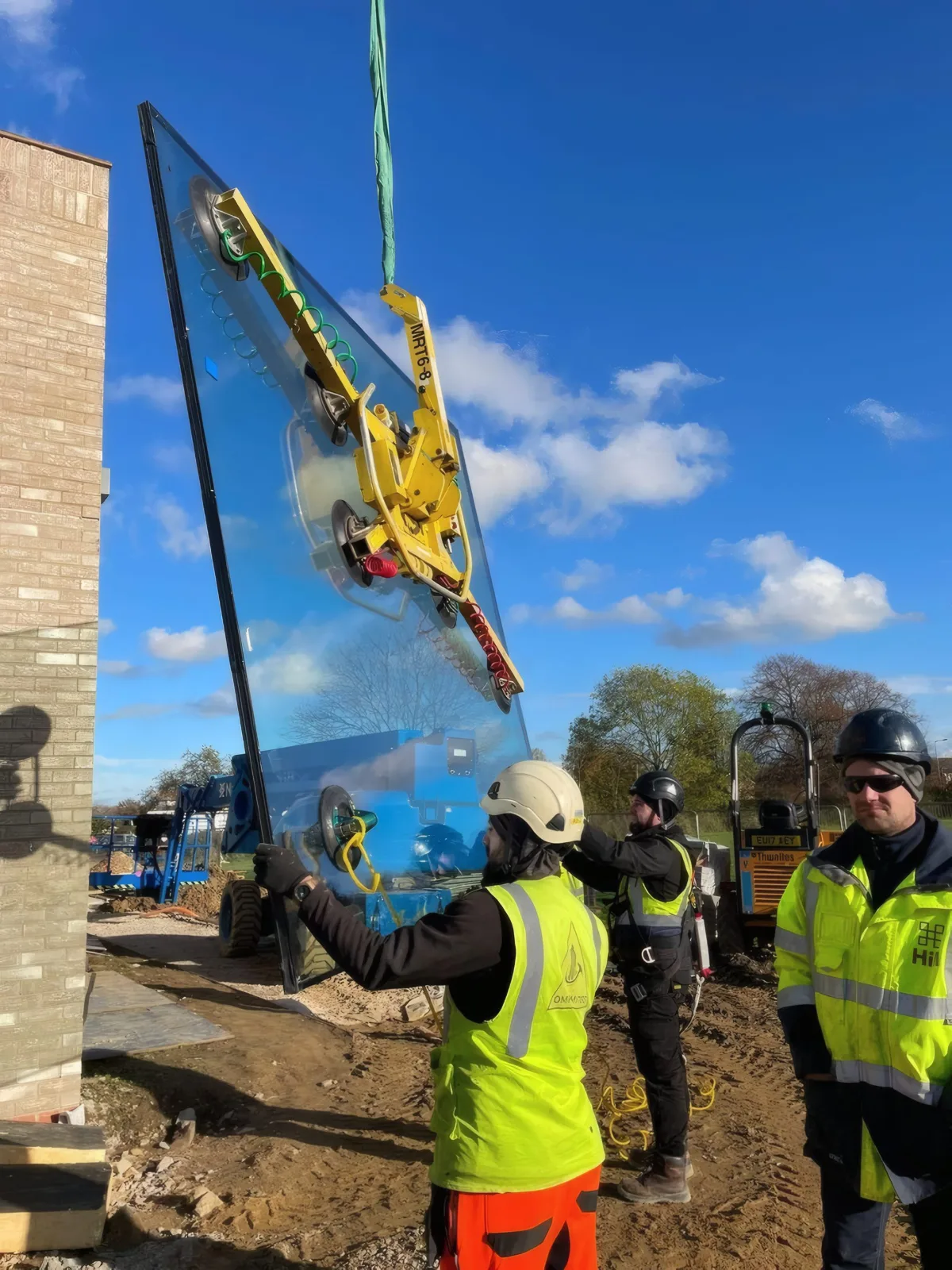 A glazing unit being lifted into position at the building corner.