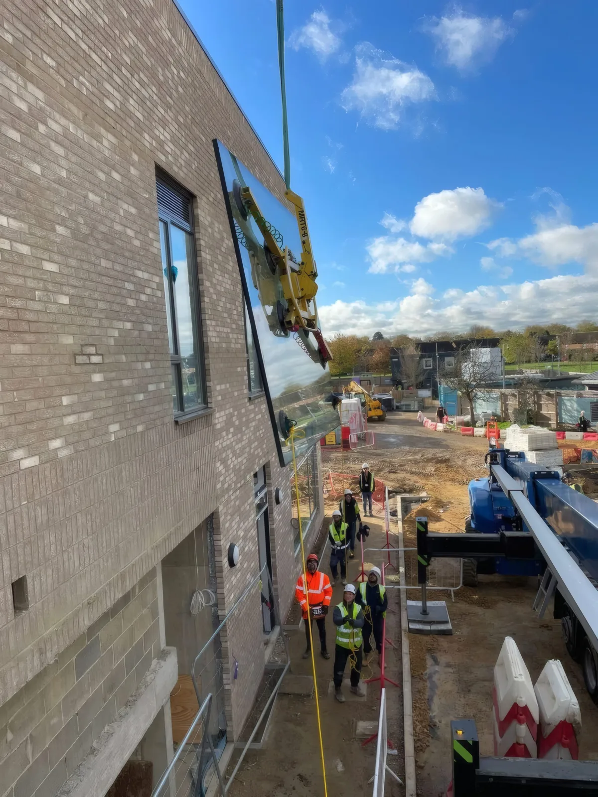 The crane extending a glazing unit up the multi-storey facade for installation.