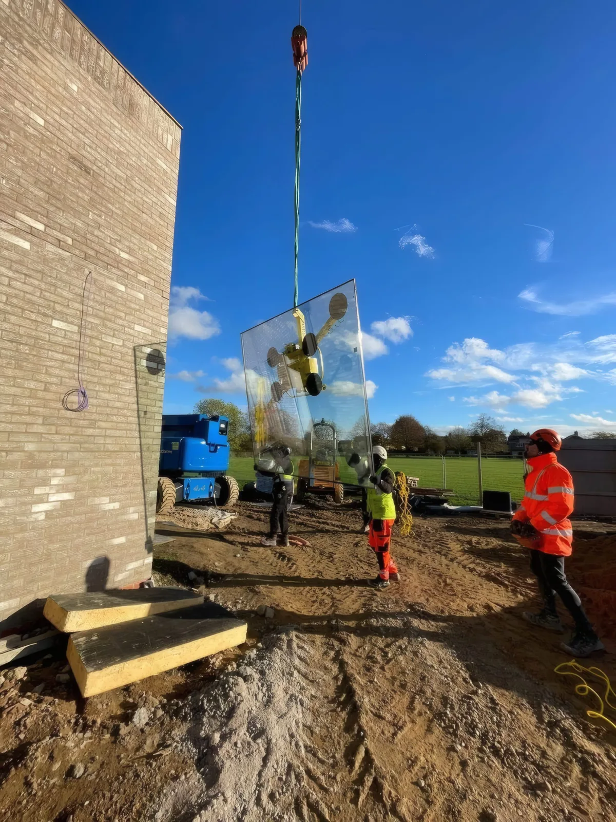 A glazing unit being fixed into place at height, working from a mobile elevating access platform.
