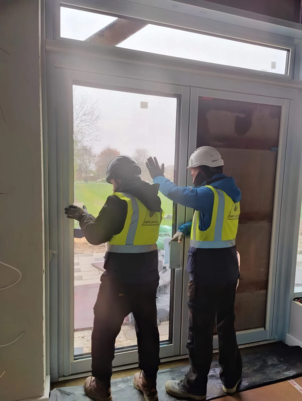 OMFC International installers fitting a glazed entrance door set.