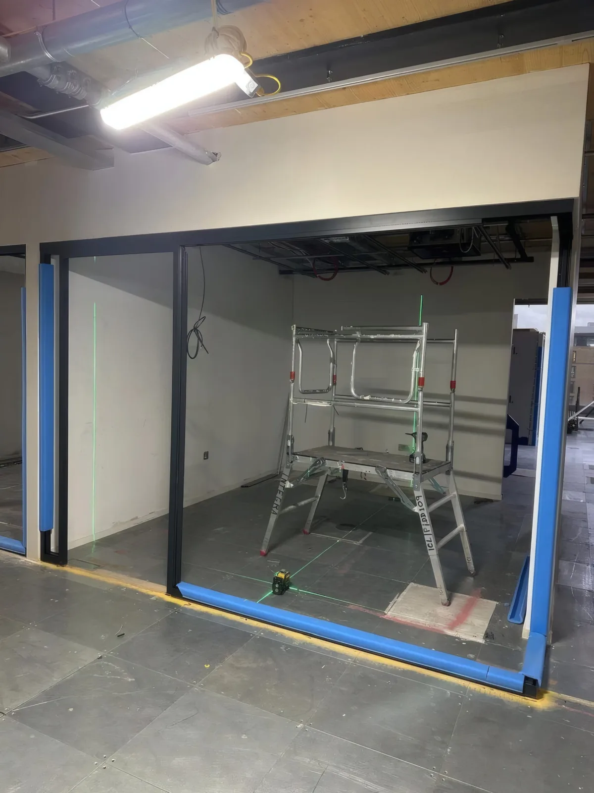 Laser level setting out for a partition frame, ensuring accurate alignment to specification.