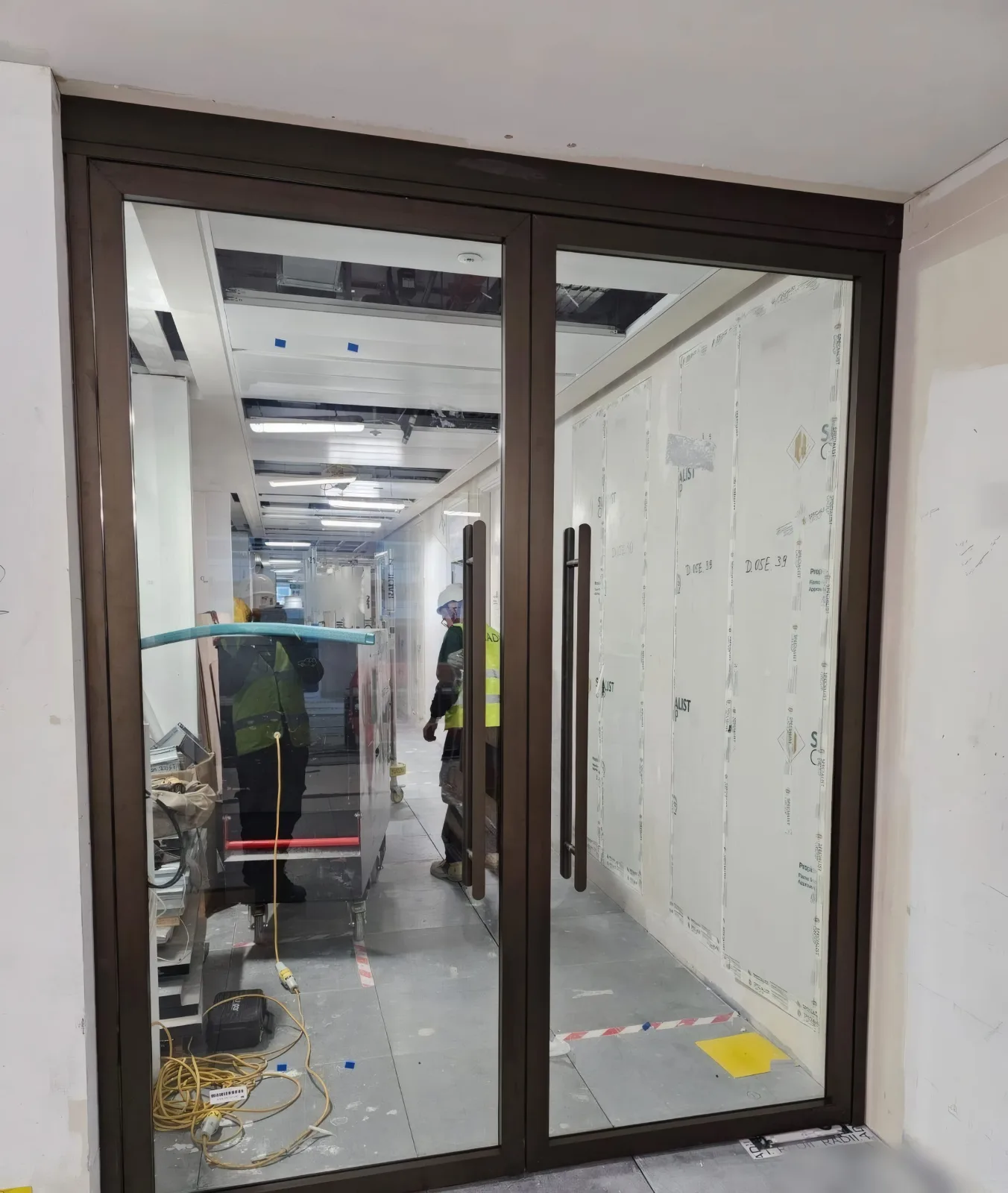 Completed glazed bronze-framed fire door set to an internal office corridor.