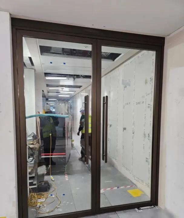 A completed glazed bronze-framed fire door set to an office corridor.