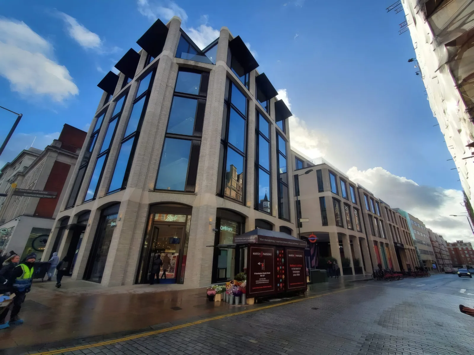 The completed mixed-use development on Kensington High Street, with its distinctive stone-faced facade and glazed corner bays.