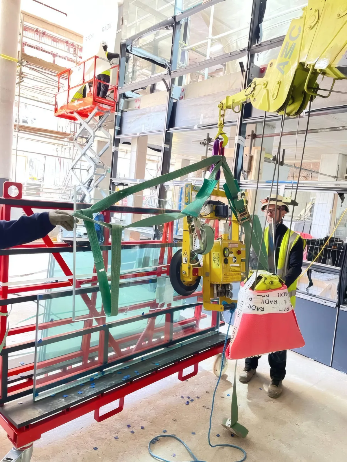 A glazing unit secured to the vacuum lifter at ground level, ready to be lifted into the facade.
