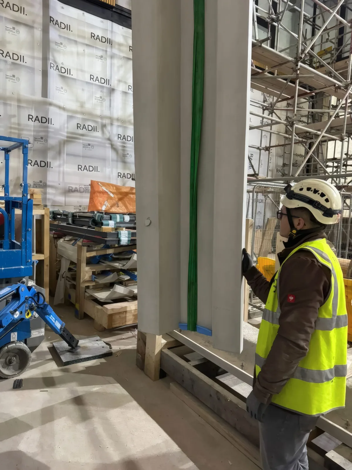 Installation in progress: a GRC cladding panel being positioned by a qualified OMFC International installer.