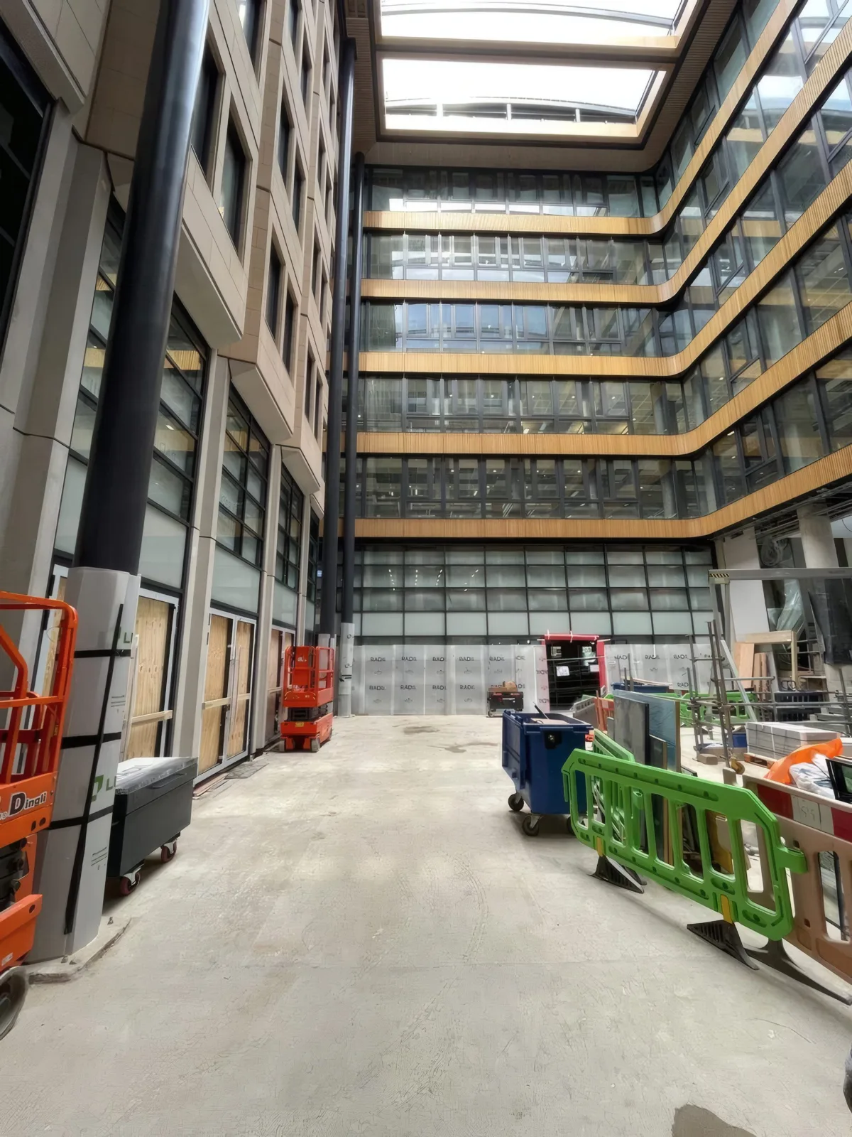 Full-height atrium facade during the later stages of installation, showing the scale of the curtain walling and cladding scope.