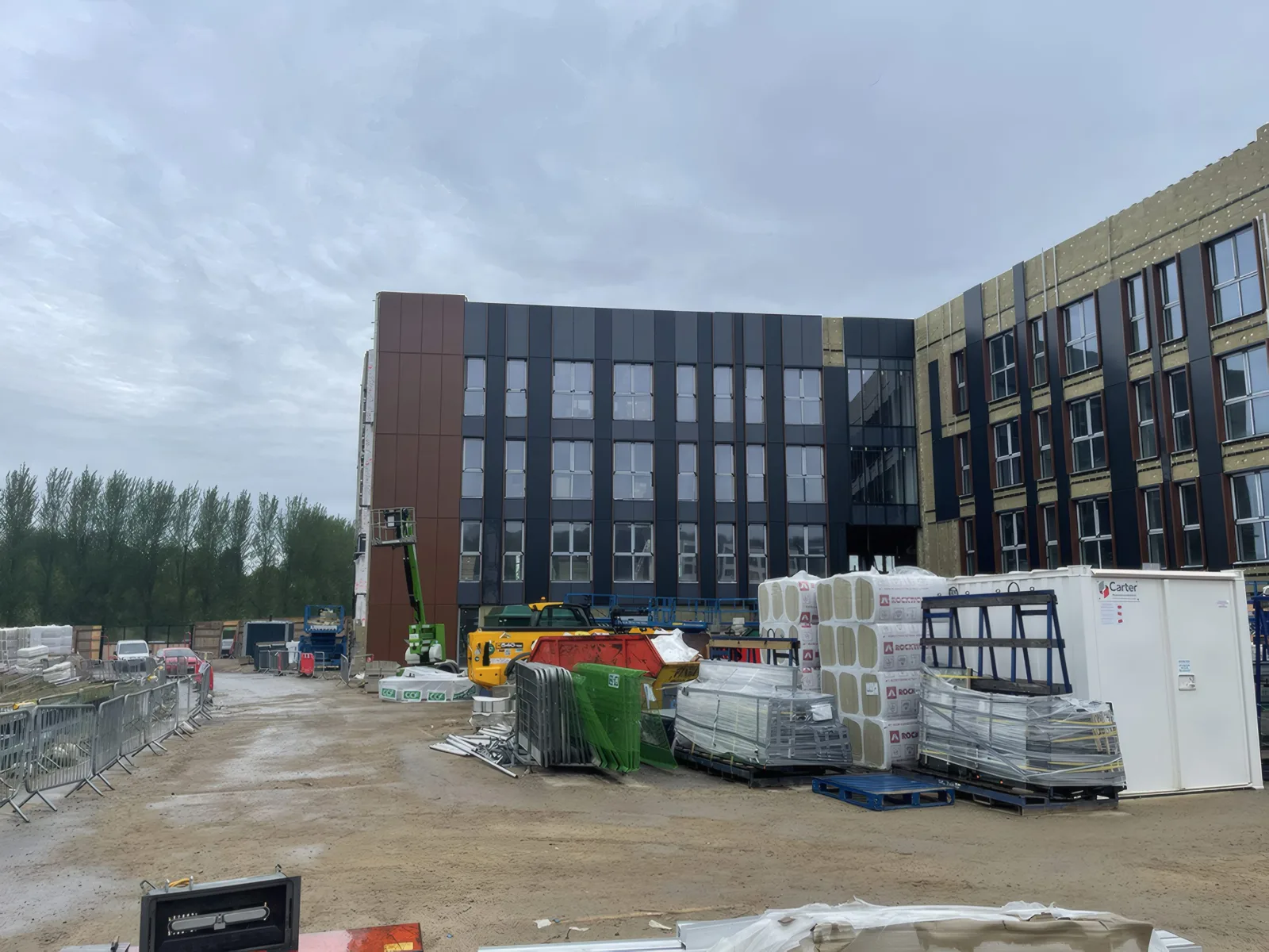 Materials laid out across the site, with the clad elevations beyond.