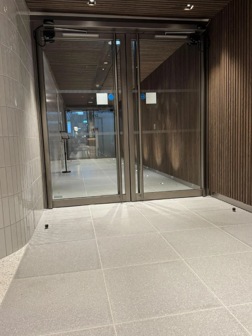 Power-operated glazed double doors with overhead sensors.