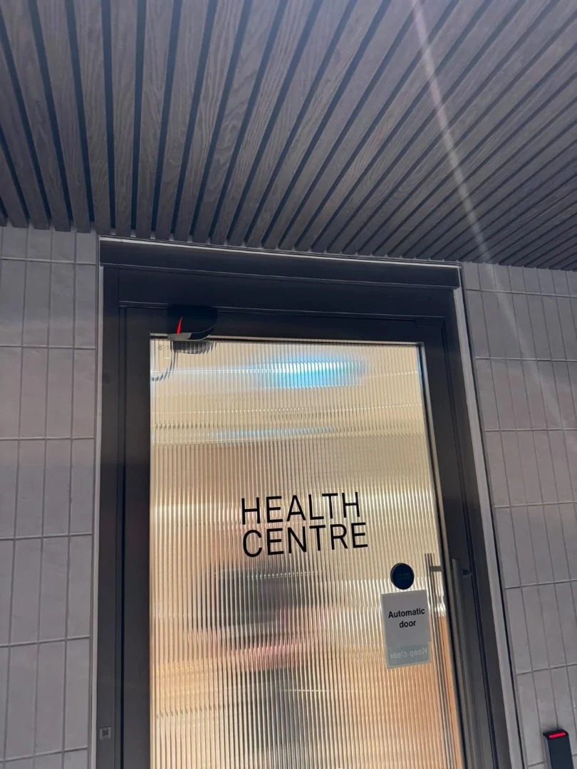 The health centre entrance door: bronze framing, reeded glass and access control.