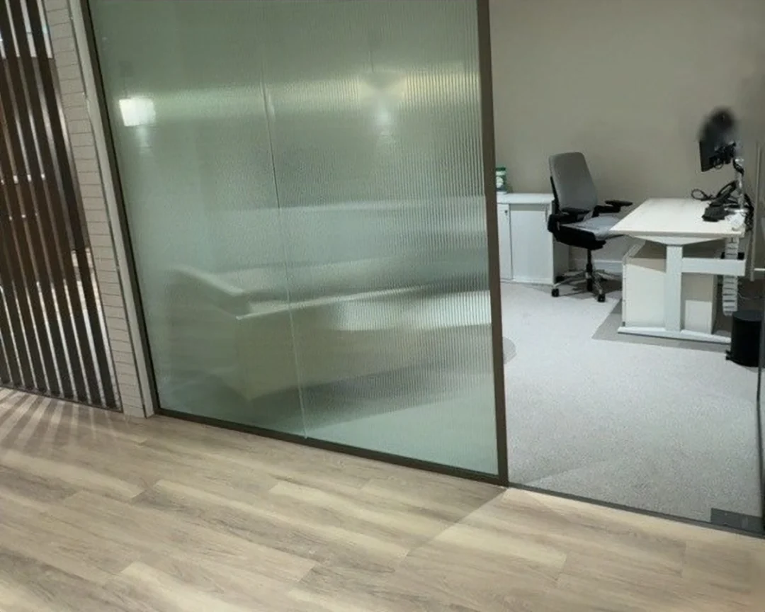 Completed office: bronze-framed reeded glass partitioning.