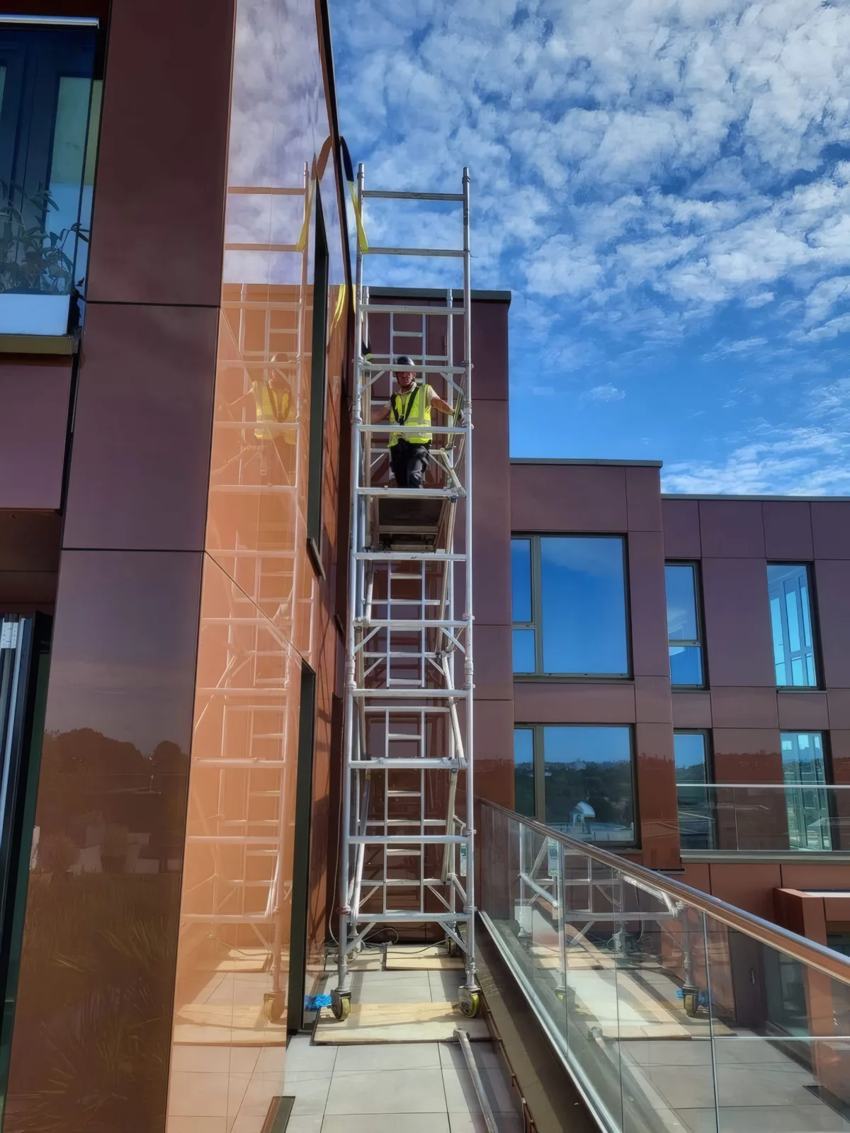 The OMFC International team working from an access tower to fit aluminium cladding panels to the upper floors.
