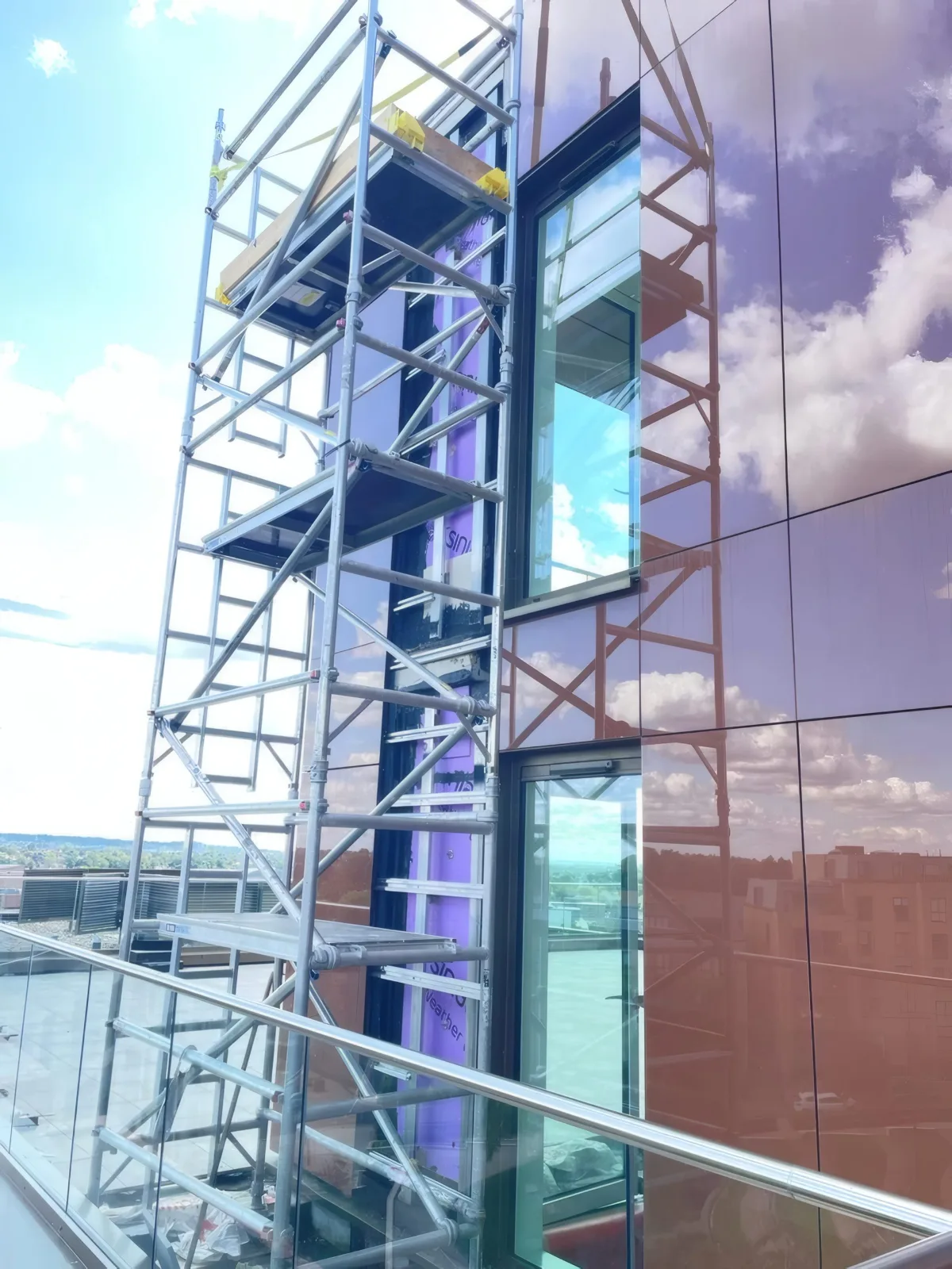 Access tower positioned at a glazed balustrade and feature cladding corner during installation.