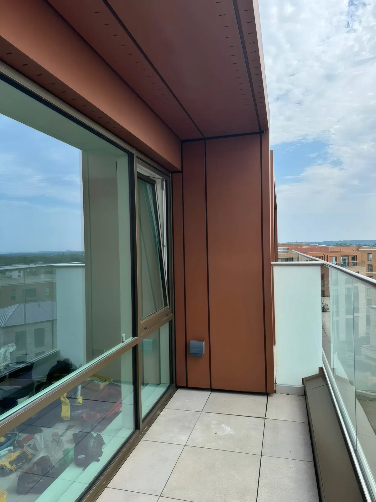 Completed balcony corner, with feature terracotta-finish cladding and glazed balustrade.
