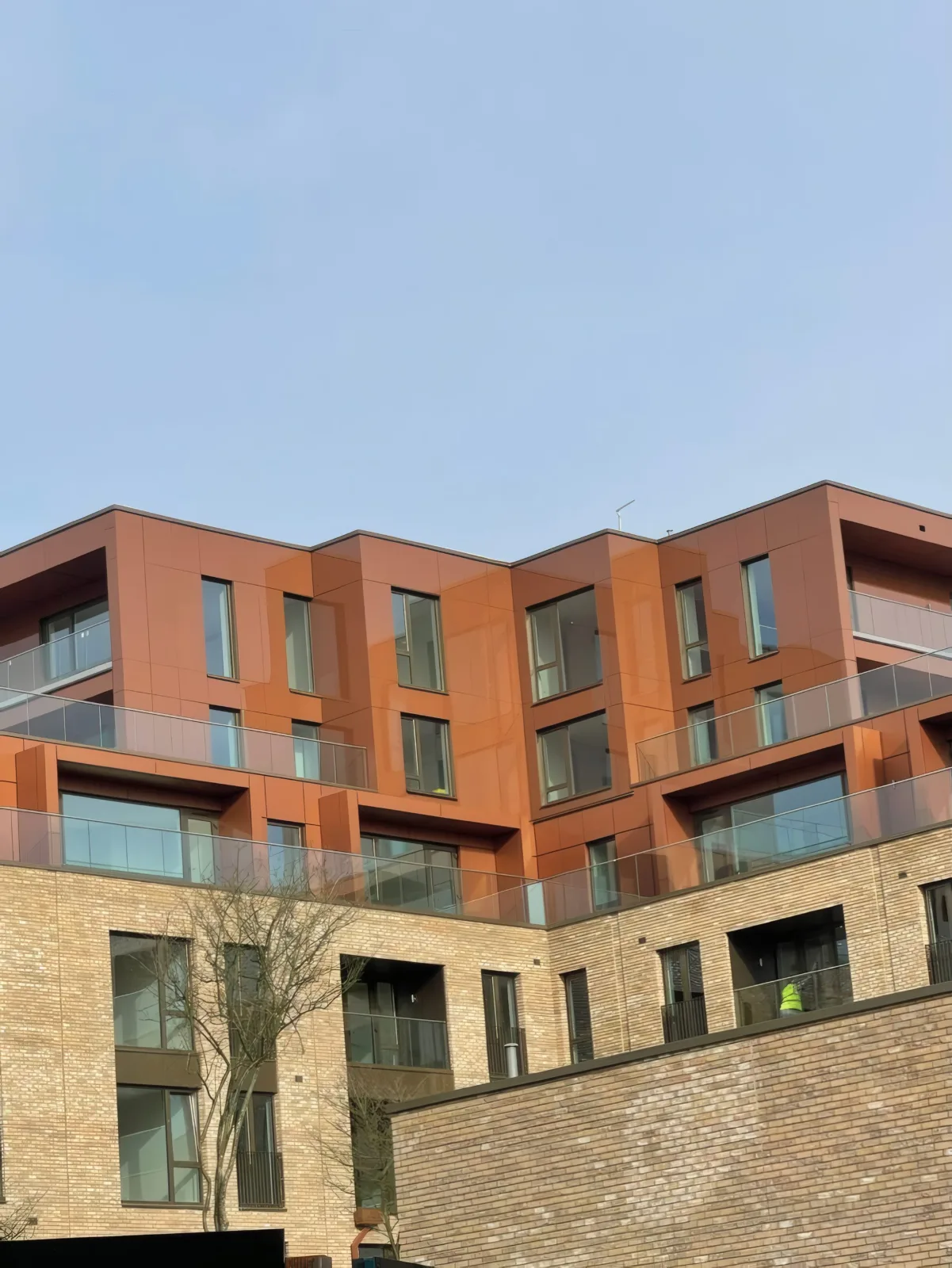 Terracotta-finish aluminium cladding installed by OMFC to the upper floors of a residential block in London.