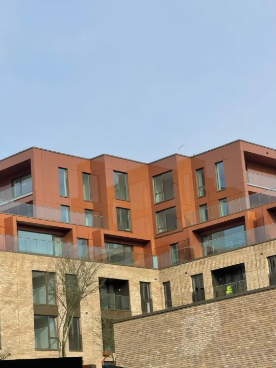 Terracotta-finish cladding to the upper floors of a residential block.