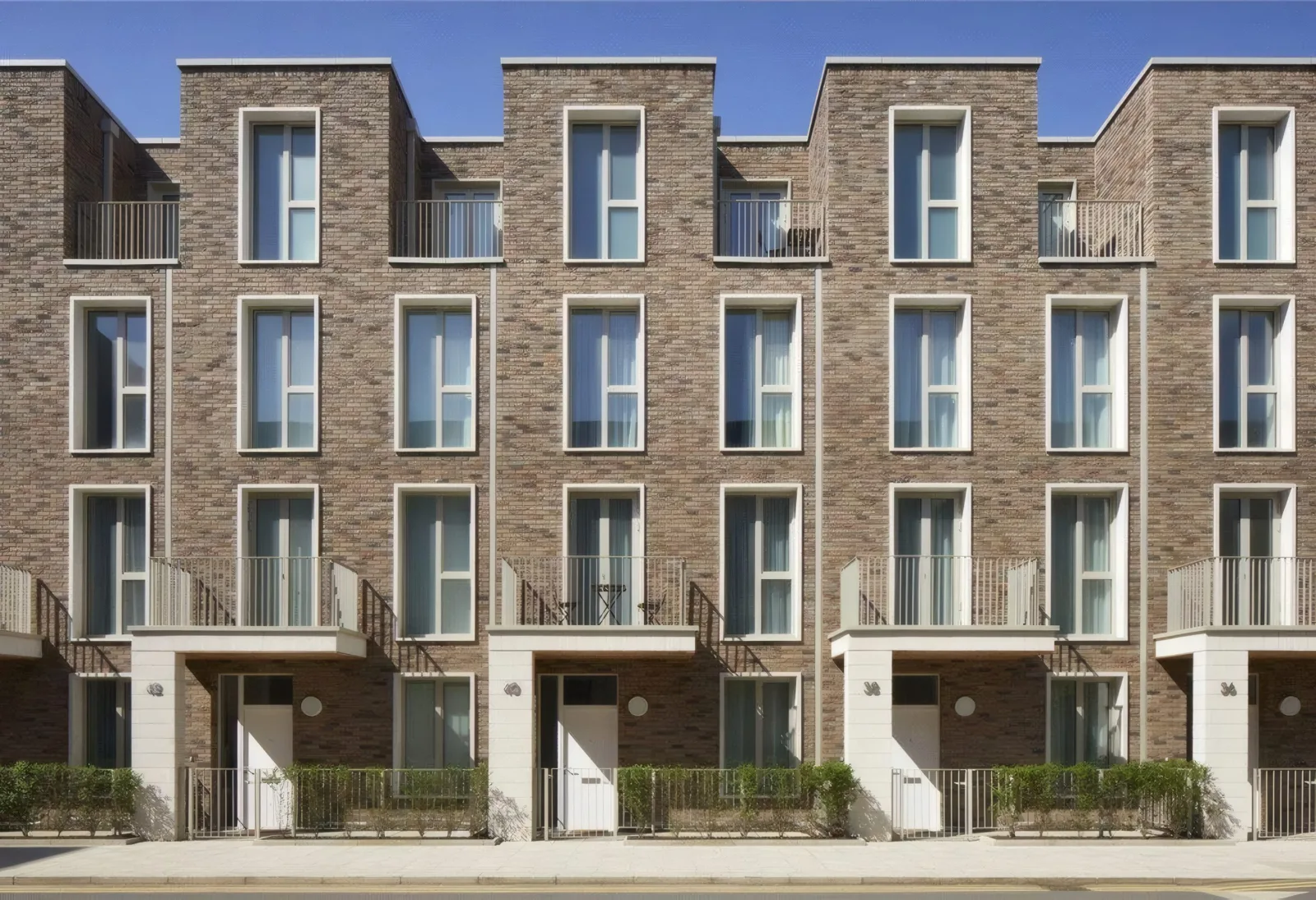 Brick townhouses with recessed balconies and front railings.