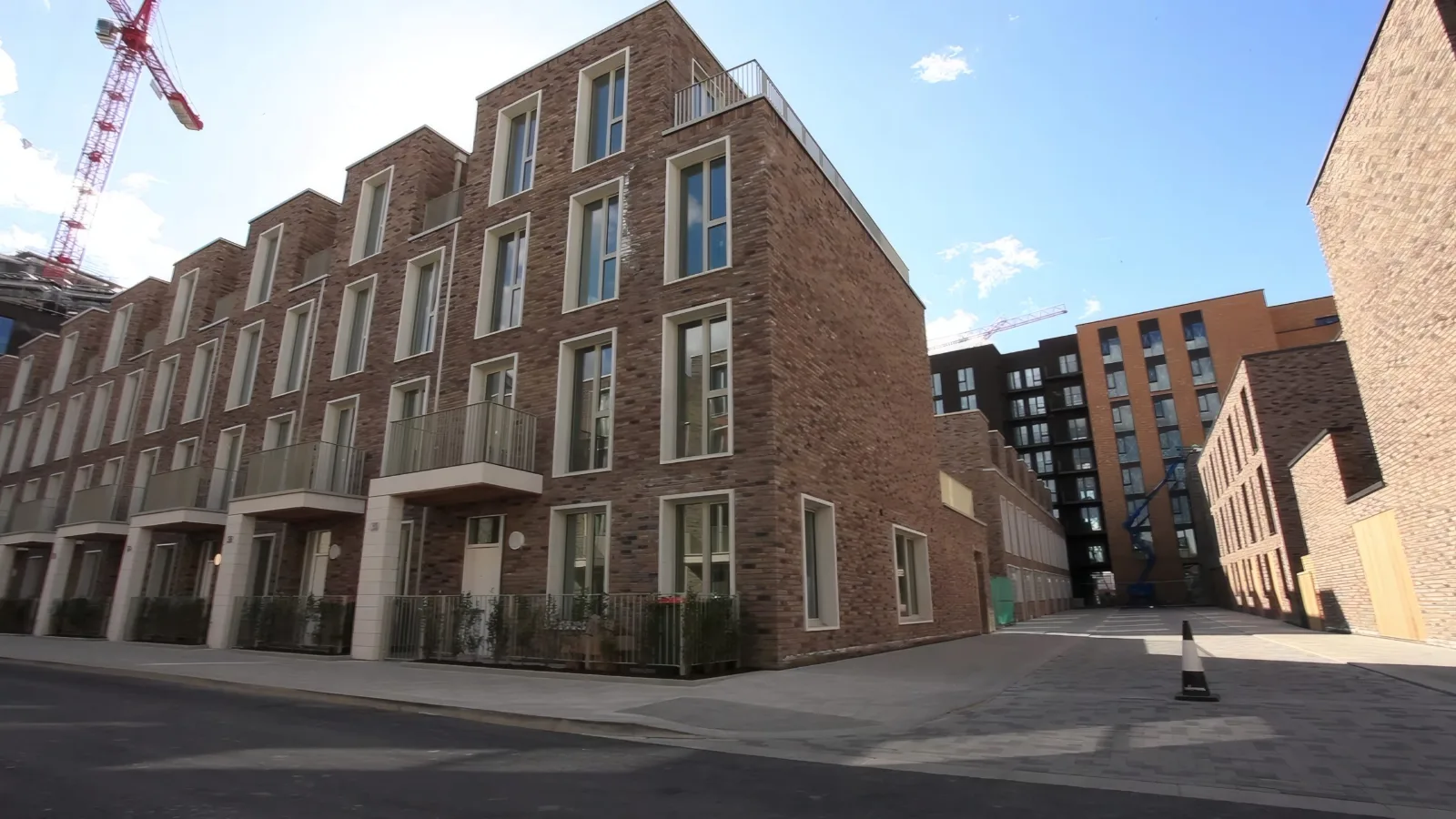 A terrace of brick townhouses, with cranes still on the skyline.