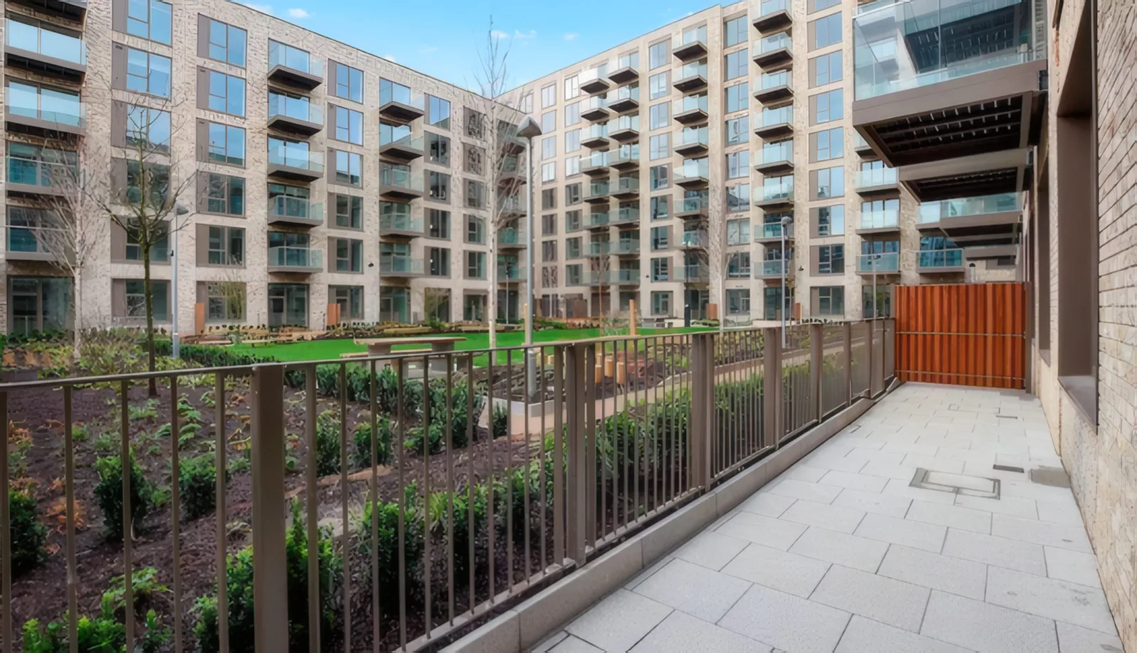 A planted courtyard and ground-floor terrace between apartment blocks.